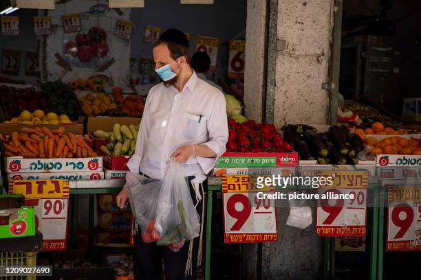 April 2020, Israel, Bnei Brak: A man goes grocery shoppint at a market ahead of Shabbat, Judaism's day of rest, in Bnei Brak, a city that has become...