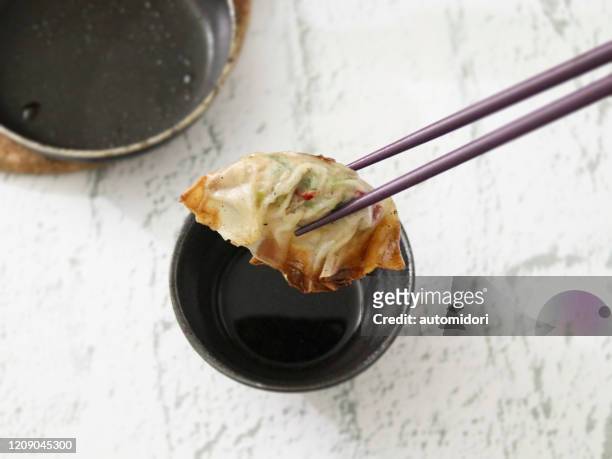 gyoza (japanese dumplings) being dipped with chopsticks - dips stock pictures, royalty-free photos & images