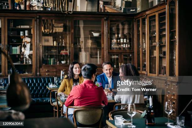 group of friends sitting at table in fancy restaurant - dining stock pictures, royalty-free photos & images