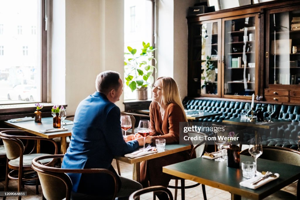 Couple Drinking Red Wine At Restaurant Table Together
