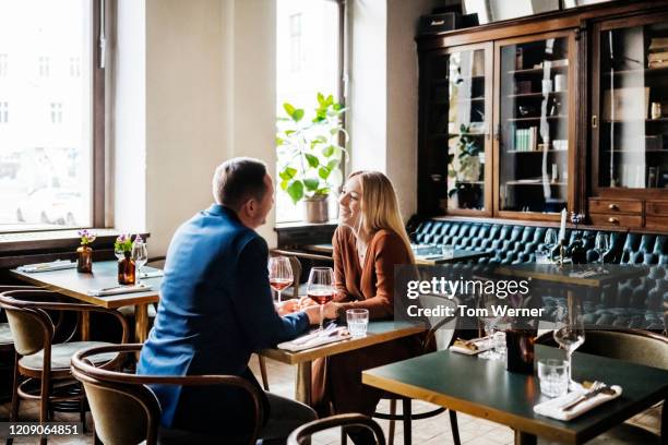 couple drinking red wine at restaurant table together - cortejar fotografías e imágenes de stock