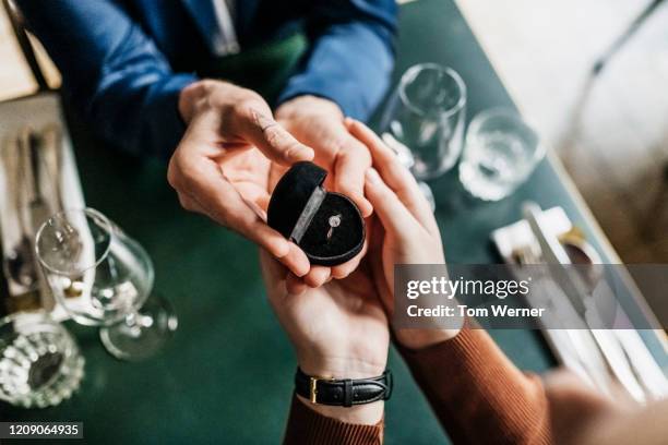 aerial view of man presenting girlfriend with engagement ring - men rings foto e immagini stock