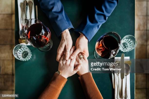 aerial view of couple holding hands at restaurant table - overhead view stock-fotos und bilder