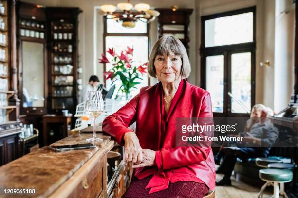 portrait of mature woman sitting at restaurant bar - red coat stock pictures, royalty-free photos & images