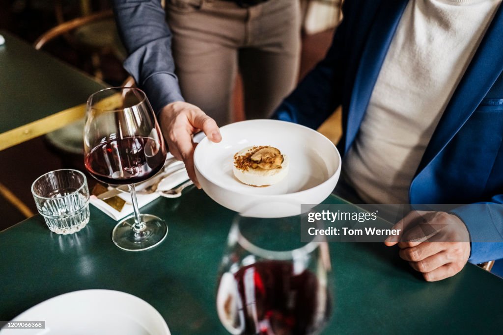 Waiter Serving Customer Starter Dish In Restaurant