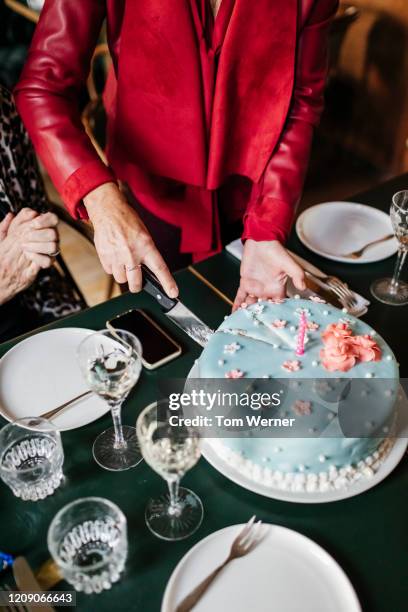 mature woman slicing birthday cake at restaurant - 80 jahre torte stock-fotos und bilder