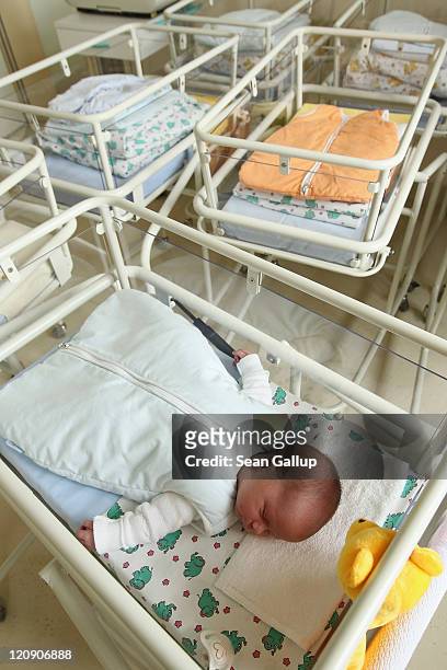 Day-old newborn baby, who has been placed among empty baby beds by the photographer, lies in a baby bed in the maternity ward of a hospital on August...