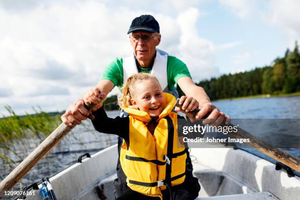 grandfather and granddaughter rowing - rowboat stockfoto's en -beelden