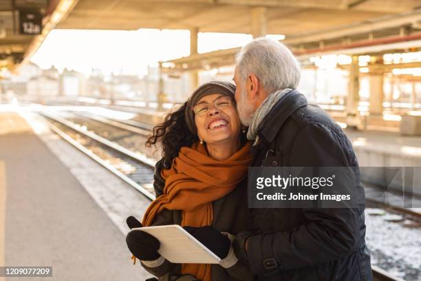 mature couple on train station platform - couple travel tablet stock-fotos und bilder