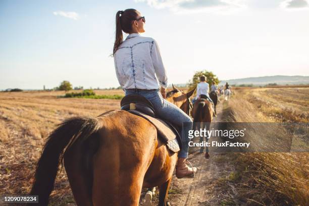 femme de touriste serein conduisant un cheval avec un groupe de touristes - cavalier photos et images de collection