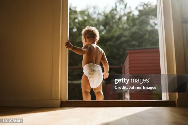 toddler standing in open door - pañal fotografías e imágenes de stock
