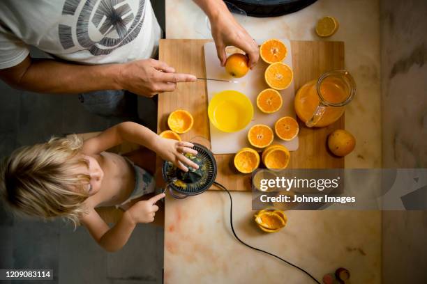 boy making orange juice with father - family orange juice stockfoto's en -beelden