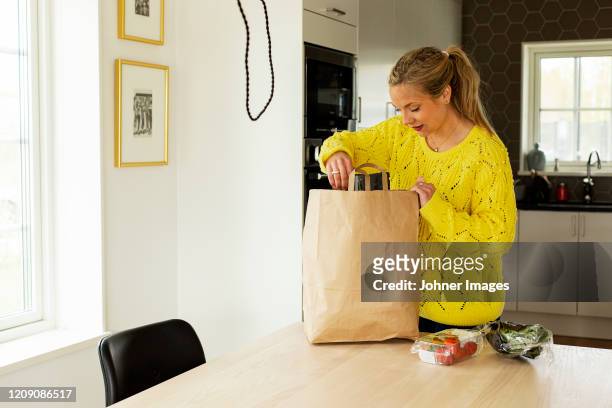 woman unpacking shopping at home - paper bag stock-fotos und bilder