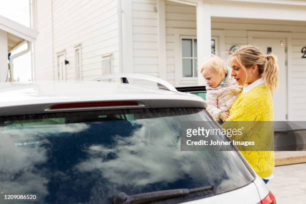 mother with daughter near car - pregnant woman car stock-fotos und bilder