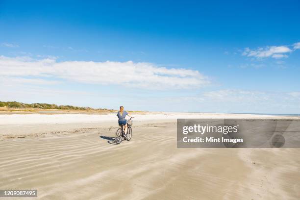 a teenage girl cycling on a beach - bottomless girls stockfoto's en -beelden