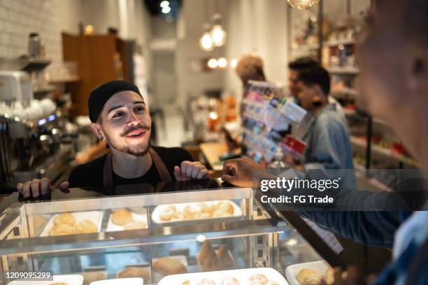 junger kellner bedient kunden im café - bar staff stock-fotos und bilder