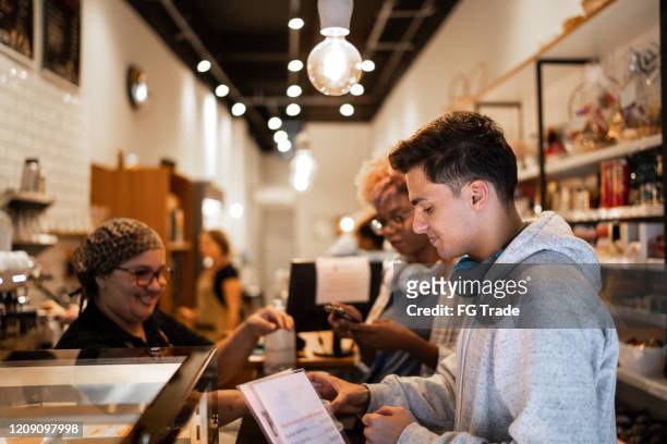 friends choosing menu in coffee shop - small business saturday stock pictures, royalty-free photos & images