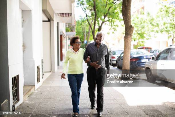 senior couple walking together on a sidewalk - couple walking shopping stock pictures, royalty-free photos & images