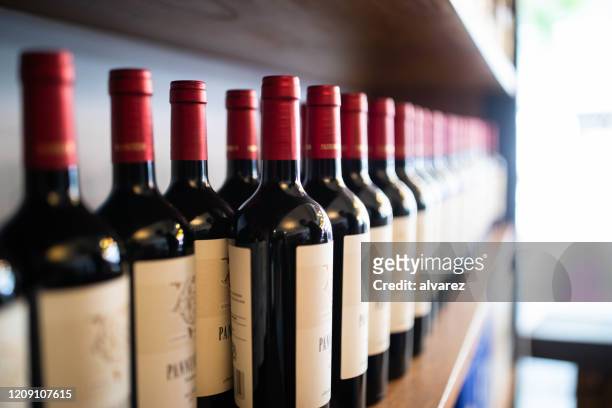 de flessen van de wijn op plank bij een wijnmakerij - empty wine glass stockfoto's en -beelden