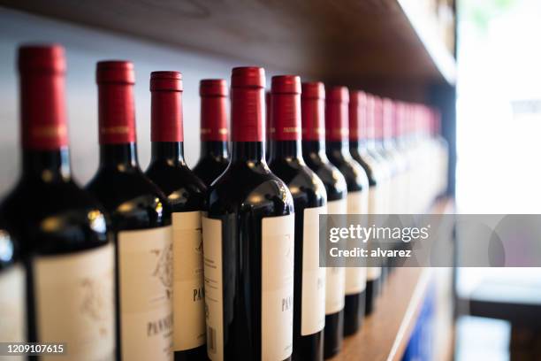 wine bottles on shelf at a winery - argentina wine stock pictures, royalty-free photos & images