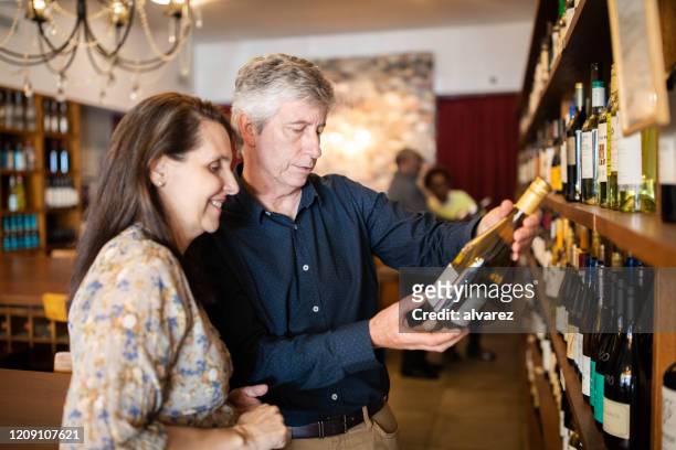 couple choosing a wine to buy at wine store - choosing wine stock pictures, royalty-free photos & images