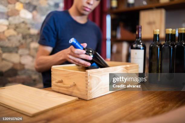 verkoper die een wijnfles in houten doos verpakking - packing parcel stockfoto's en -beelden