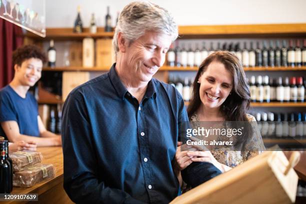 couple looking happy after purchasing wine - wine cellar stock pictures, royalty-free photos & images