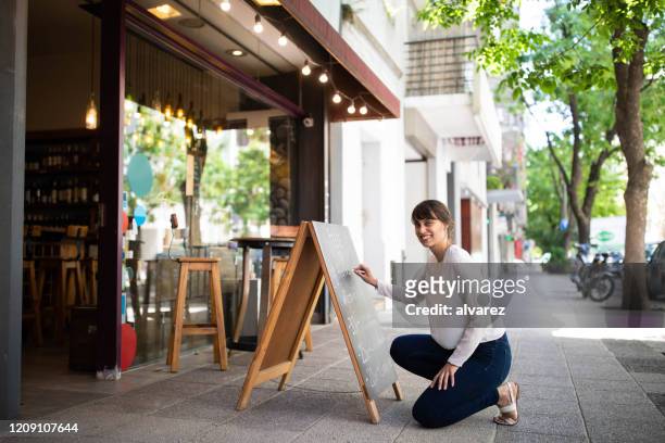 employee at chalkboard outside wine shop - blackboard women stock pictures, royalty-free photos & images