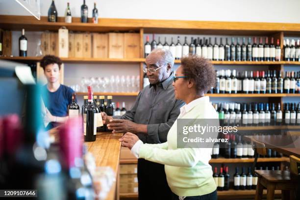 senior couple buying wine at a winery - buying alcohol stock pictures, royalty-free photos & images