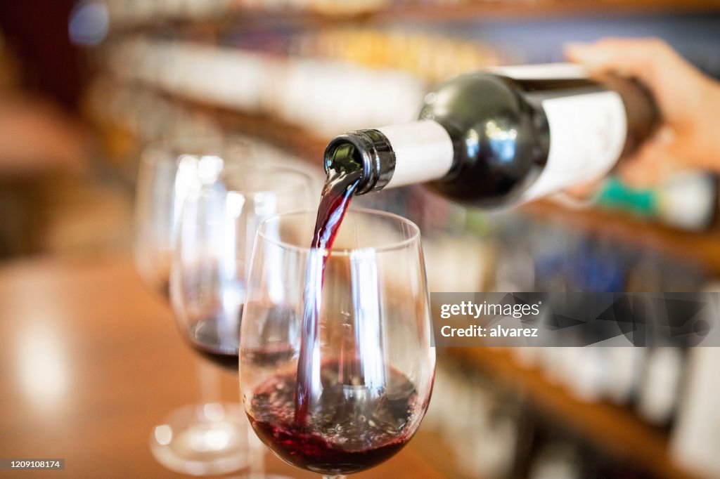 Bartender gießt Wein in Gläser