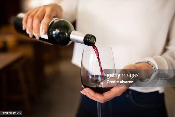 woman serving red wine in a winery - drink bottle stock pictures, royalty-free photos & images