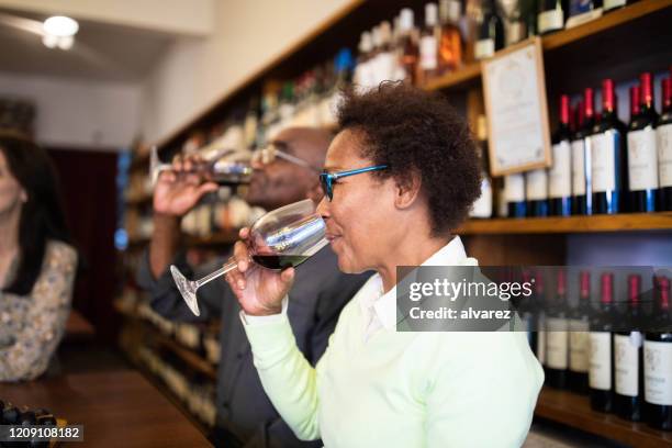 mature female having wine in a winery tasting room - taste test stock pictures, royalty-free photos & images