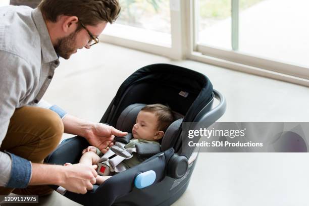 new dad straps baby into infant car seat - baby carrier stock pictures, royalty-free photos & images