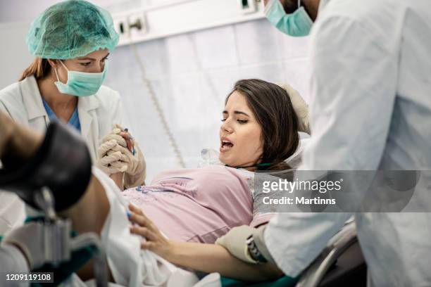 in het ziekenhuis vrouw bevalling ondersteuning, verloskundigen assisting. moderne delivery ward met professionele verloskundigen - giving birth stockfoto's en -beelden