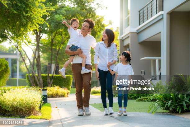 asian young happy family of four walking together outdoor. parents with son and daughter look happy and smile. happiness and harmony in family life. - family smile stock-fotos und bilder