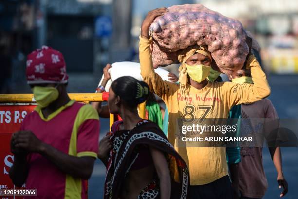 Migrant workers carrying sacks of groceries distributed at their workplace walk on a street during a government-imposed nationwide lockdown as a...