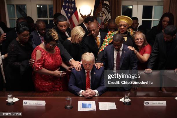 African American supporters lay their hands on U.S. President Donald Trump as they pray for him at the conclusion of a news conference and meeting in...