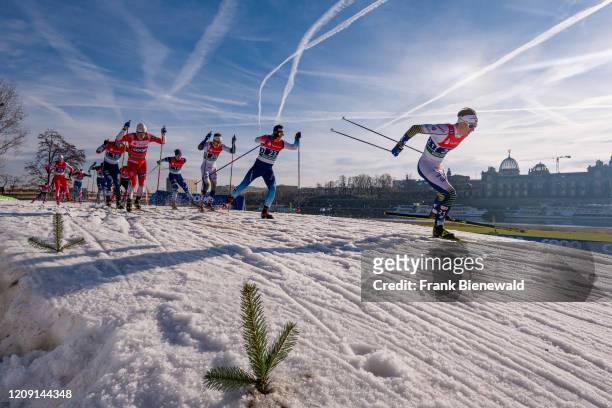 Men racing at the FIS cross-country skiing sprint World Cup on the banks of the river Elbe, the skyline of the baroque town in the distance.