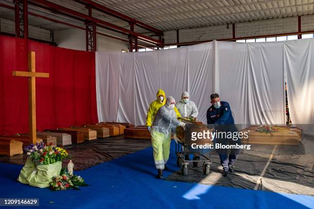 Members of the civil protection and Carabinieri, transport a coffin, containing a victim of coronavirus, from a re-purposed warehouse of a road...