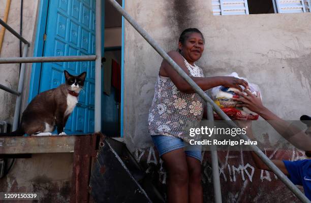 Resident of Jardim do Vale das Virtudes Favela receives a pack of food at Campo Limpo neighborhood on April 4, 2020 in Sao Paulo, Brazil. According...