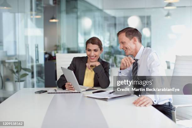 businesspeople using digital tablet in office in dubai, smiling. - expatriado fotografías e imágenes de stock