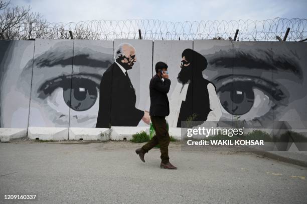 Man wearing a facemask as a precautionary measure against the COVID-19 novel coronavirus walk past a wall painted with images of US Special...