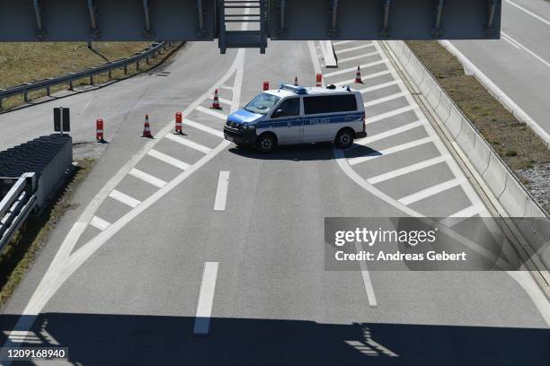 German police car blocks the A7 motorway at a checkpoint at the border to Austria, where crossings have been severely restricted in an effort to rein...