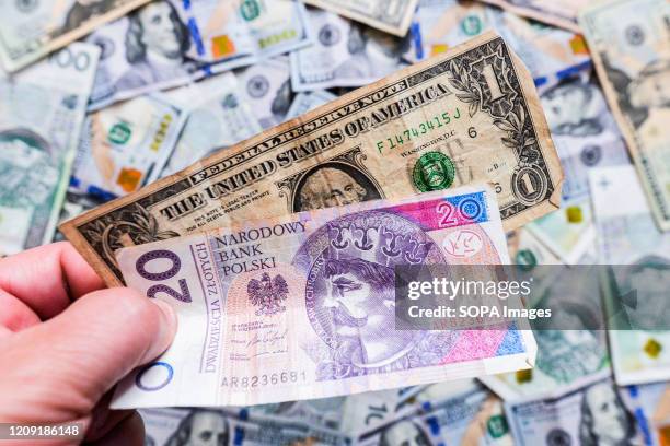 In this photo illustration a twenty Polish Zloty and a one US Dollar banknotes, with a background view of one hundred Polish Zloty and one hundred US...