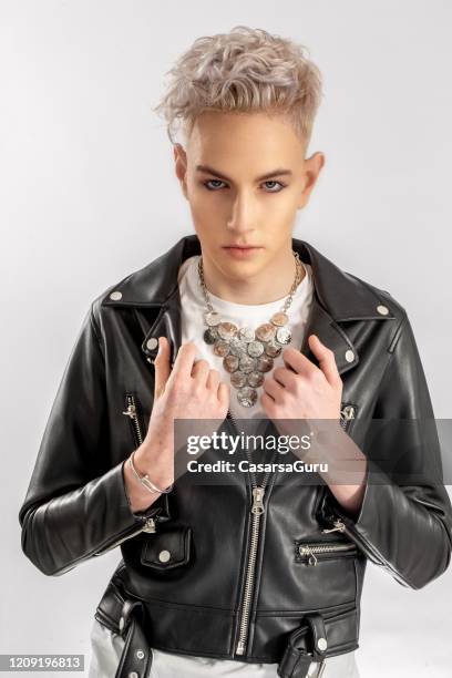 waist up portrait of fashionable teenage boy grabbing the collar of his leather jacket in front of white background - stock photo - androgynous boys stock pictures, royalty-free photos & images