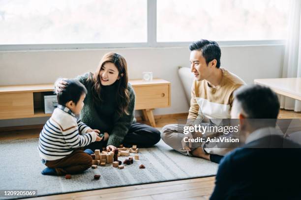 joyful asian parents and grandparent sitting on the floor in the living room having fun and playing wooden building blocks with little son together - parents applauding stock pictures, royalty-free photos & images
