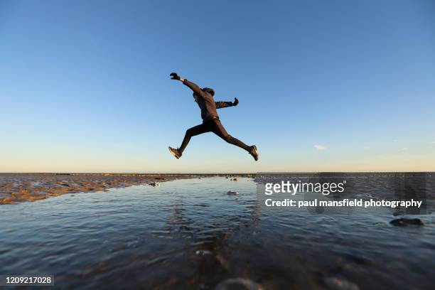 boy jumping over stream - leap of faith modo di dire inglese foto e immagini stock