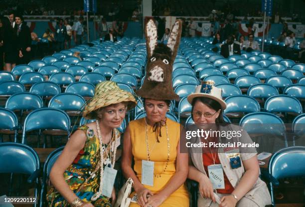 Three female Democratic Party members wearing distinct hats, two wear different styles of straw hat and the third wears hat in the shape of a donkey,...