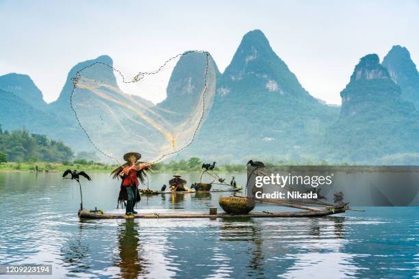 pescatore su una barca di bambù, fiume li, cina - bamboo raft foto e immagini stock