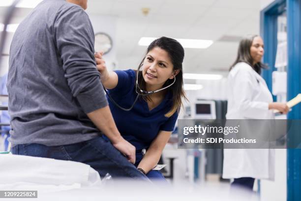 emergency room nurse listens to senior man's heart - serviço de urgência imagens e fotografias de stock